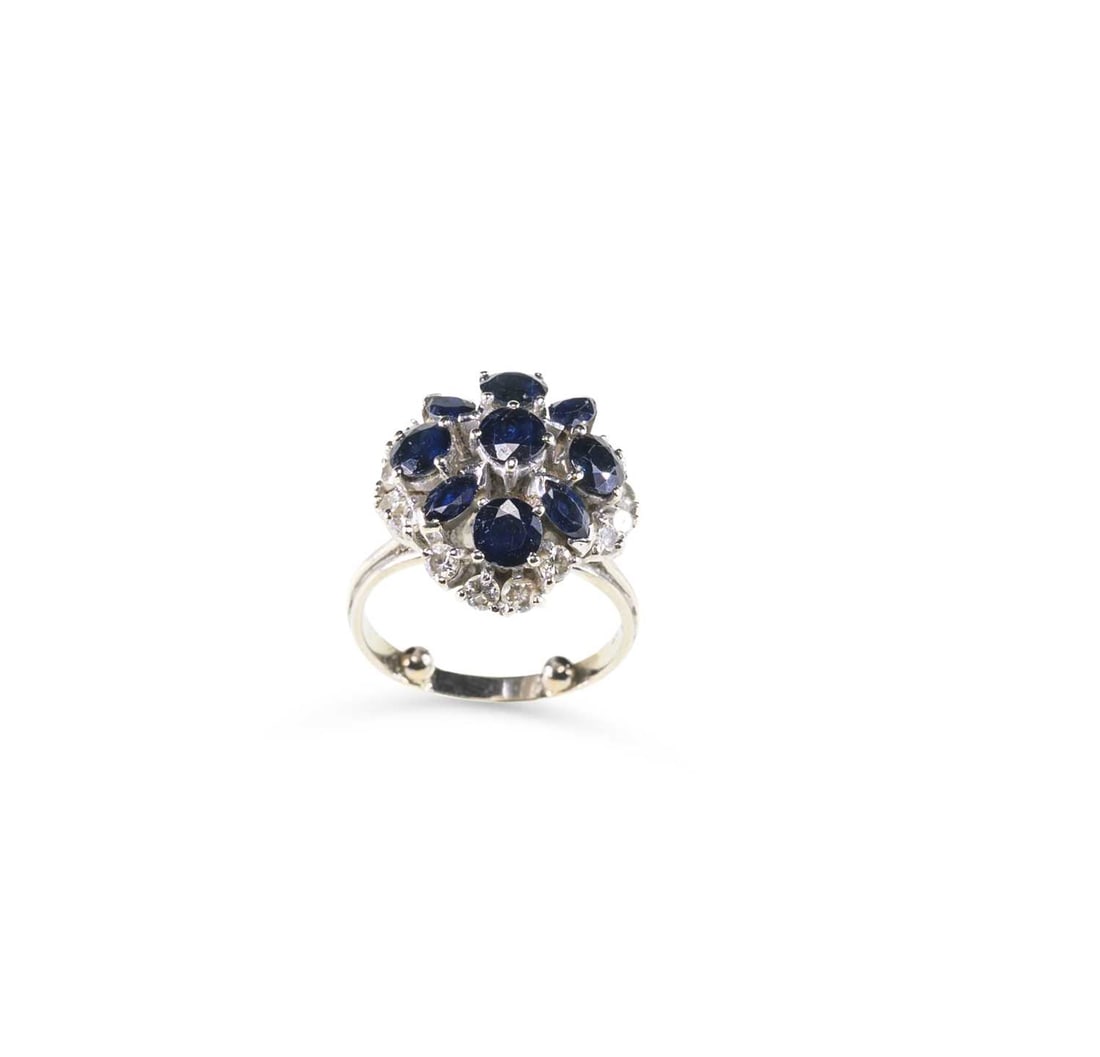A SAPPHIRE AND DIAMOND CLUSTER RING: A SAPPHIRE AND DIAMOND CLUSTER RING round-cut and marquise-cut sapphires within an undulating border of round-cut diamonds, stamped '18CT'. Estimated total diamond weight 0.80, ring size I, 7.1 grams 