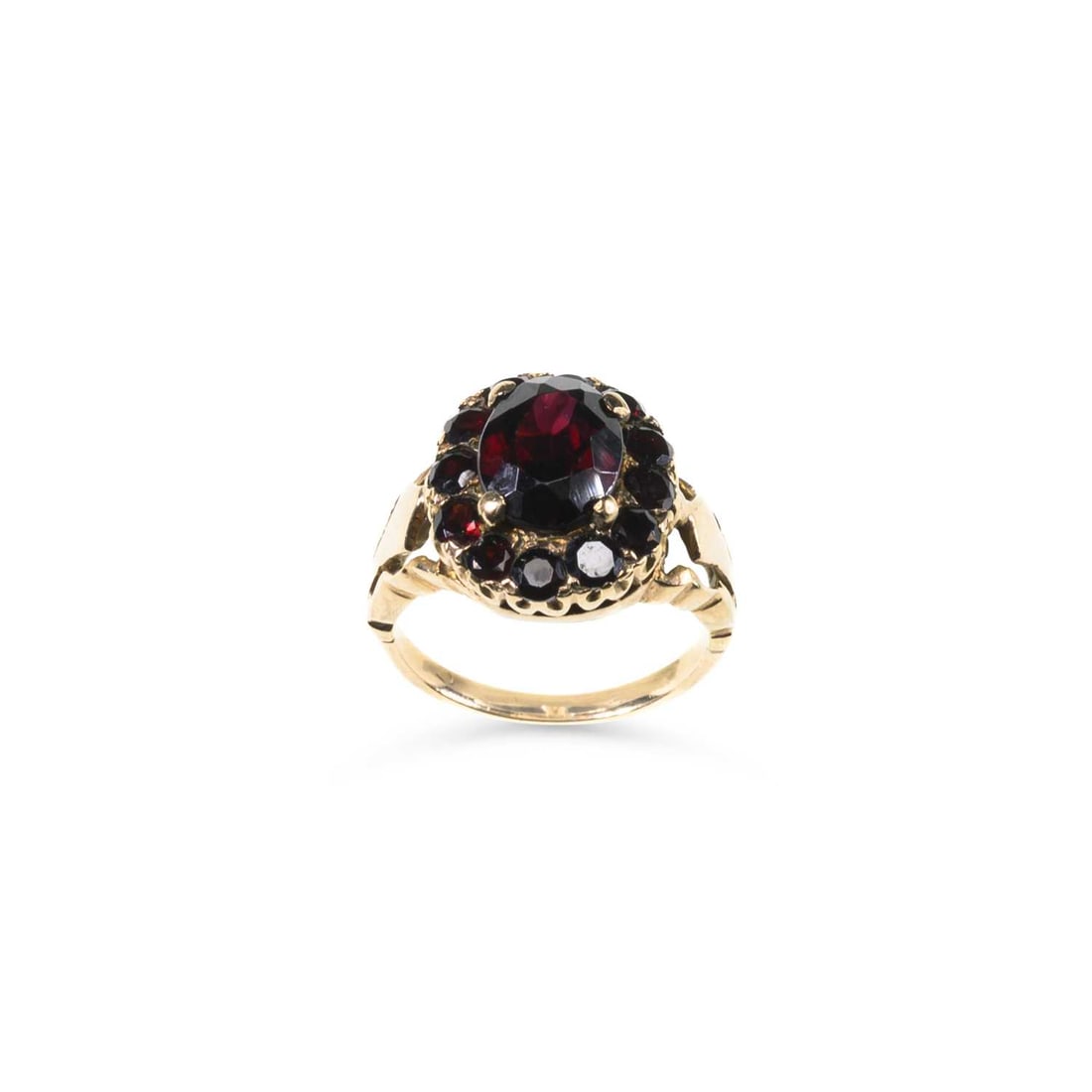 A GARNET CLUSTER RING: A GARNET CLUSTER RING an oval-cut garnet within an border of round-cut garnets, to fancy shoulders, unmarked. Ring size J1/2, 4.1 grams Good condition.
