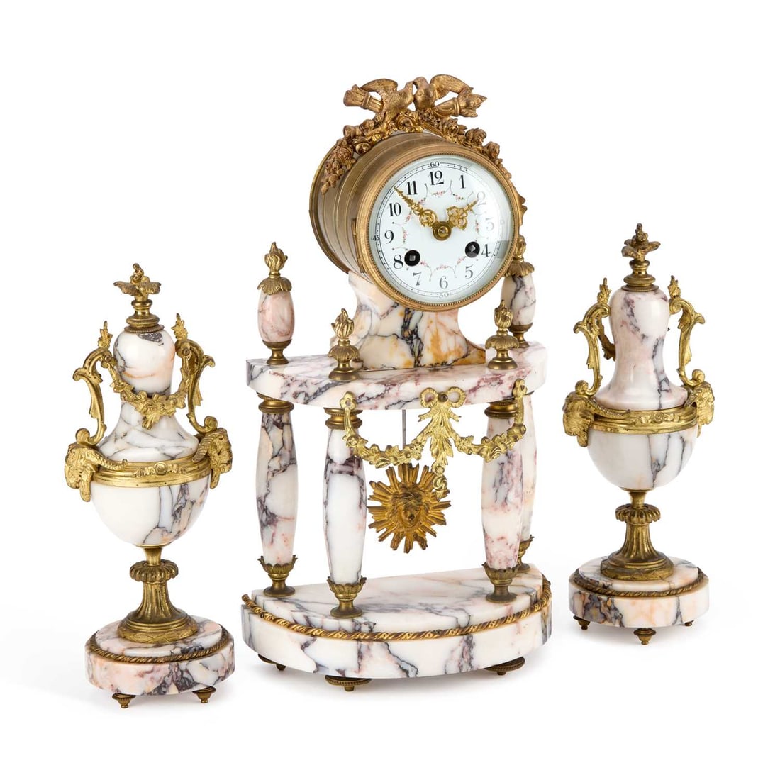 A FRENCH GILT-METAL AND MARBLE CLOCK GARNITURE LATE 19TH CENTURY: A FRENCH GILT-METAL AND MARBLE CLOCK GARNITURE LATE 19TH CENTURY the clock with a cylinder case surmounted by a crest of love birds and crossed torches, raised on a demilune base with four reverse tap