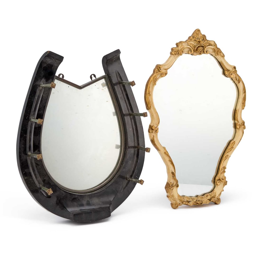 A HORSESHOE SHAPED MIRROR CIRCA 1900: A HORSESHOE SHAPED MIRROR CIRCA 1900 the ebonised wood mirror frame as a horseshoe, with the nails forming the coat hooks; together with a gilt rococo scroll shaped mirror. (2) First 48cm by 38.5cm