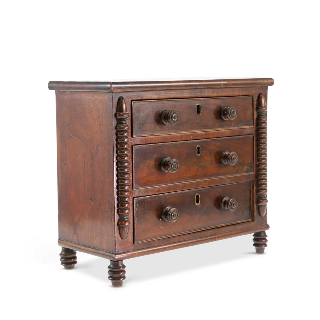 A VICTORIAN MAHOGANY MINIATURE CHEST OF DRAWERS: A VICTORIAN MAHOGANY MINIATURE CHEST OF DRAWERS with three long drawers flanked by turned mouldings, raised on turned feet. 28.5cm high, 32cm wide, 16cm deep