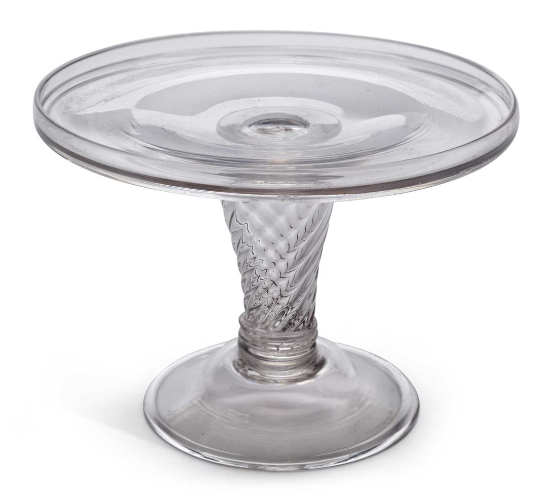 AN GLASS TAZZA 18TH CENTURY: the dished top with a folded rim, raised on a multiple spiral air twist stem, on a domed folded foot. 23cm diameter, 17cm high