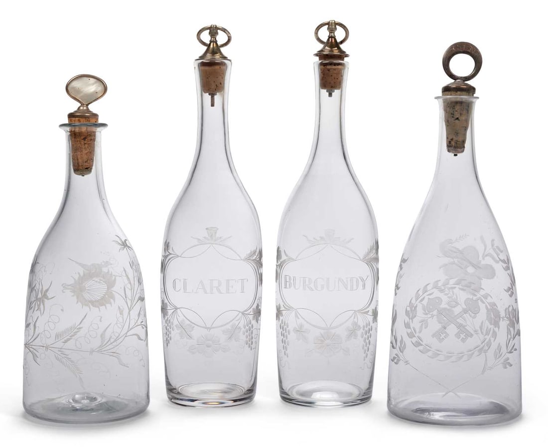 FOUR GLASS DECANTERS 18TH CENTURY AND LATER: each of tapering form, one engraved with a bird and a floral spray with a mother of pearl mounted stopper, one engraved CLARET and another BURGUNDY within cartouches hung with vine and flowers, with m