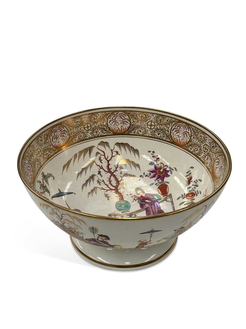 A MINTON PORCELAIN PUNCHBOWL CIRCA 1820: set upon a circular pedestal foot, painted internally with a Chinoiserie scene of figures in a garden, beneath a broad band of elaborate gilt scrollwork, enclosing circular panels of flowering plants,