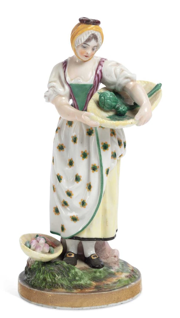 A FRENCH NIDERVILLER PORCELAIN FIGURE CIRCA 1820: modelled as a young girl gathering vegetables, set upon a circular grassy mound base, edged in gilt. 19.5cm high
