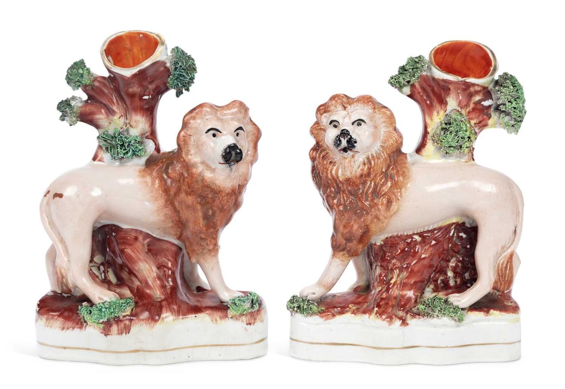 A PAIR OF STAFFORDSHIRE LION SPILL VASES 19TH CENTURY: each modelled as a lion standing before a tree stump forming the spill vase, applied with moss and raised on a shaped oval base. (2) 16.5cm high