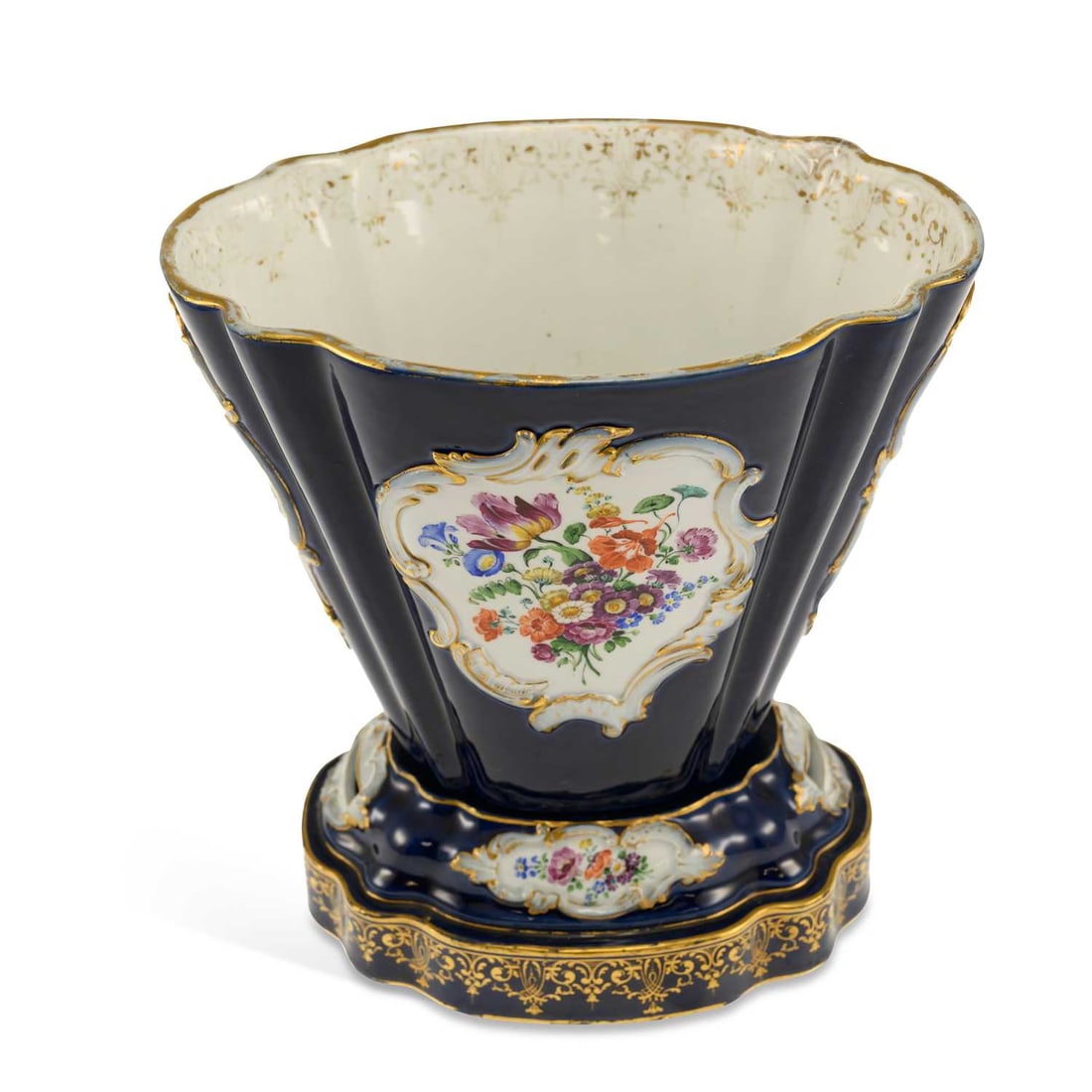 A MEISSEN PORCELAIN CACHEPOT AND STAND CIRCA 1870: Sevres style, painted with panels of figures in 18th Century costume and a spray of flowers, on a cobalt blue ground, the stand with panels of flowers, underglaze blue crossed swords marks. 26cm high 