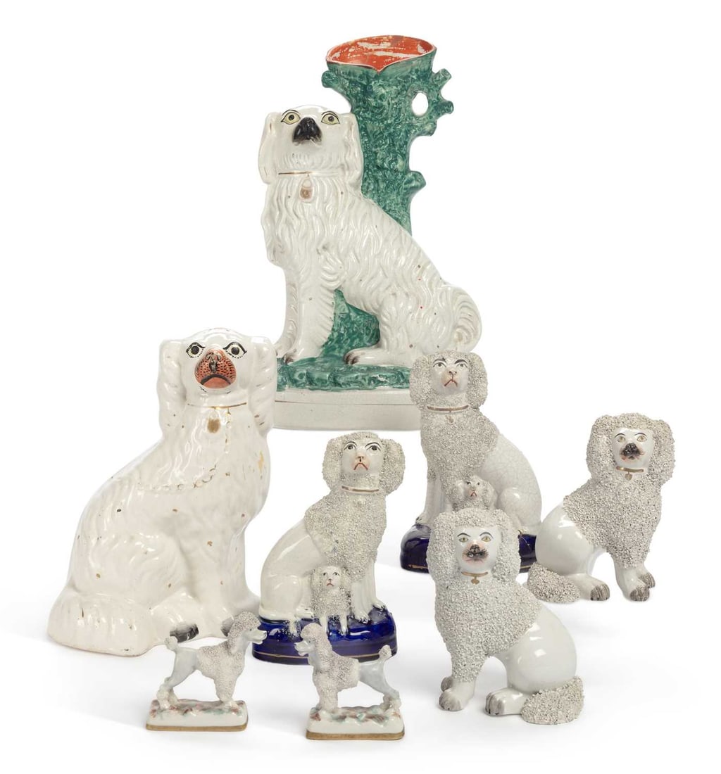 A PAIR OF STAFFORDSHIRE POTTERY POODLES CIRCA 1850: the seated Poodles, having separate front legs, and wearing gilt collars; together with a pair of seated Poodles, and their puppies, set upon oval cobalt blue bases; a seated Spaniel spill vase; a