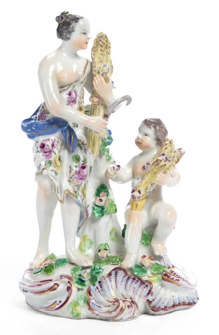 A BOW PORCELAIN FIGURE OF SUMMER CIRCA 1765: modelled as a classical maiden carrying a sickle and a sheaf of wheat, accompanied by a seated putti, set upon a rocaille moulded base, edged in gilt and puce. 19.5cm high