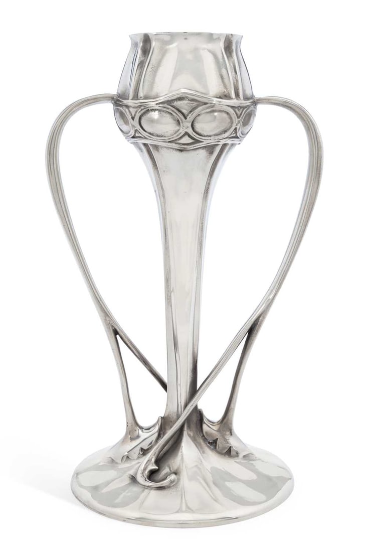 ARCHIBALD KNOX (1864-1933) FOR LIBERTY & CO A TUDRIC PEWTER TULIP VASE: no. 029, the tapering stem with a bulbous neck issuing sinuous tendril handles, all raised on a circular base, stamped marks. 25.3cm high