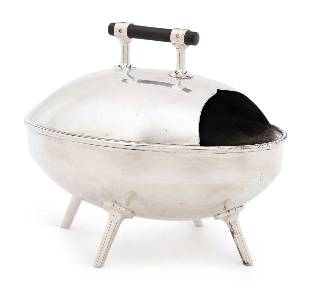 CHRISTOPHER DRESSER (1834 - 1904) FOR HUKIN & HEATH, AN ELECTROPLATED SPOON WARMER LATE 19TH CENTURY: of oval form, with a shaped aperture for a spoon, turned ebonised handled, on four strut feet, stamped to base H&H and numbered 2693. 15.5cm by 9.5cm by 13.5cm