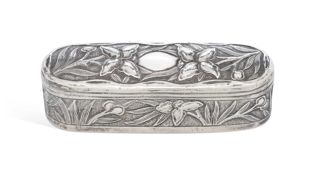 AN INDIAN SILVER ART NOUVEAU BOX: by J. Manikrai, Karachi, of rounded oblong form, with a hinged cover, embossed with an iris motif, bearing marks to base and stamped T95. 12.2cm wide, 3.8 troy ounces