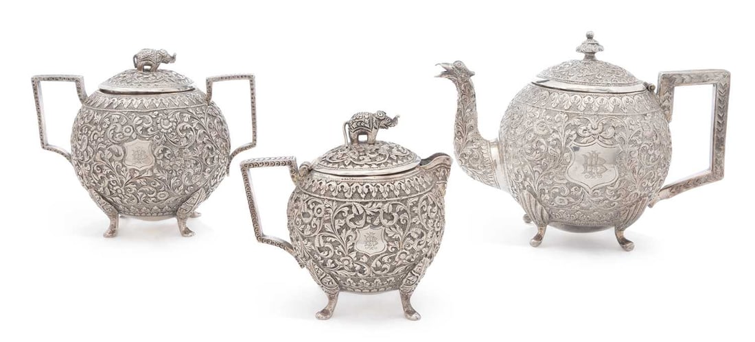 AN INDIAN SILVER KUTCH THREE-PIECE TEA SERVICE: circa 1890, comprising a teapot, covered sugar bowl and covered cream jug, each decorated with dense floral scroll, having elephant finials and set upon paw feet. (3) Teapot 12cm high, 25.2 troy ounce
