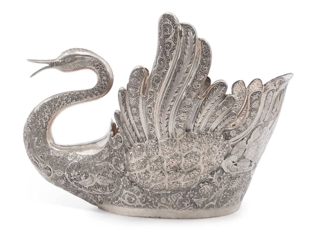 A LARGE PERSIAN (IRANIAN) SILVER SWAN TABLE CENTRE BOWL 20TH CENTURY: marked 84, modelled with wings aloft and open beak, finely chased with floral, foliate and scroll motif, the rear decorated with a figural scene of musicians and merchants before a castle. 32cm by