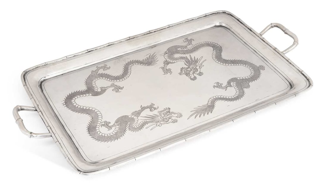 A CHINESE EXPORT SILVER TWO-HANDLED TRAY EARLY 20TH CENTURY: marked TL and 85, of rectangular form, with simulated bamboo handles and borders, engraved with a pair of four-toed dragons against a stippled ground, on four compressed bun feet. 45cm by 24.75cm,