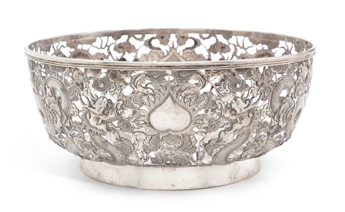 A CHINESE EXPORT PIERCED SILVER 'DRAGON' BOWL LATE 19TH/ EARLY 20TH CENTURY: maker's mark HM, of circular form, pierced and chased with four-toed dragons amongst prunus, with vacant cartouche and reeded rim, raised on a circular foot. 20cm diameter, 17.5 troy ounces Scratches 