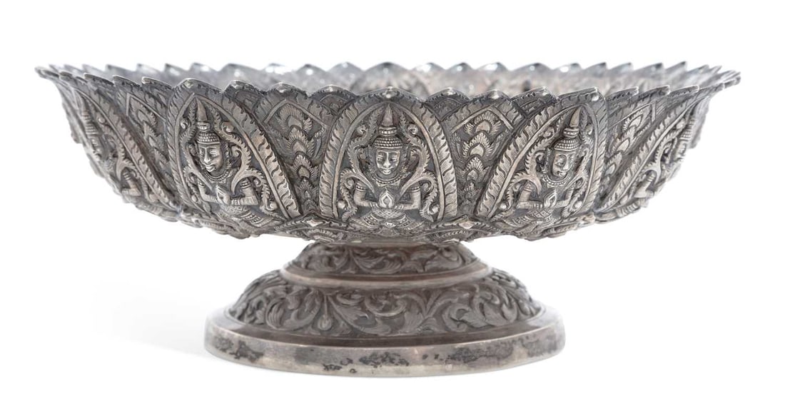 A THAI SILVER PEDESTAL LOTUS BOWL: with stylised leaf-shaped rim, repousse decorated with repeating figural motif and lotus flower pattern within an arch border, marked to the base. 23.5cm wide, 9.25cm high, 20.5 troy ounces Good