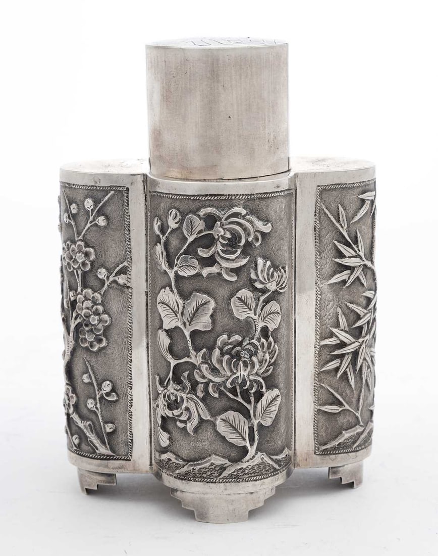 A CHINESE EXPORT SILVER TEA CADDY LATE 19TH/ EARLY 20TH CENTURY: mark of Wang Hing & Co., Hong Kong, of quatrefoil form, chased with panels of a four-toed dragon, prunus blossom and bamboo, the detachable cover engraved with a character mark, raised on four shaped 