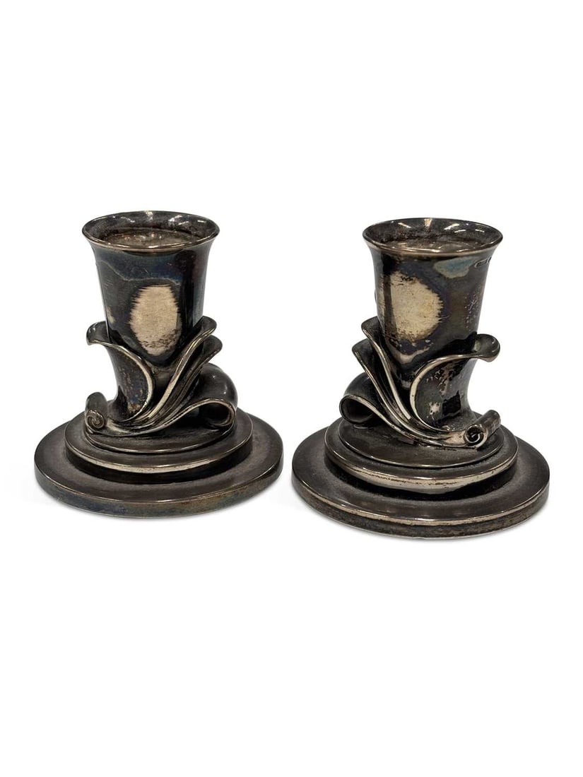 HARALD NIELSEN FOR GEORG JENSEN: A PAIR OF DANISH STERLING SILVER CANDLESTICKS: bearing import marks, numbered 604 A, of stylised foliate form, on a spreading circular stepped foot. (2) 5.5cm high, 6 troy ounces gross