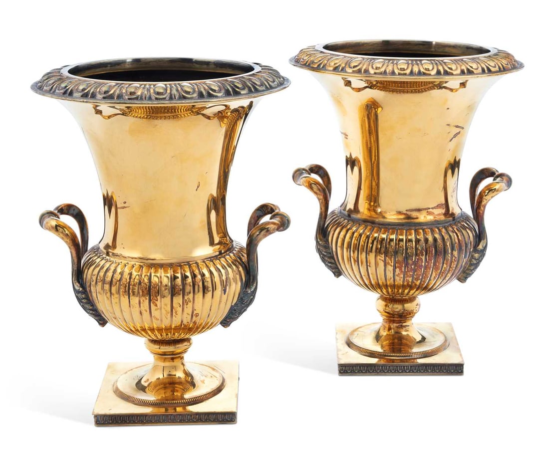 A PAIR OF ITALIAN SILVER-GILT WINE COOLERS: 800 standard, each of campana form with an egg and dart rim, twin leaf-capped scroll handles, the lower body gadrooned, on a square plinth base with stiff leaf border. (2) 25.5cm high, 80.4 troy ounce