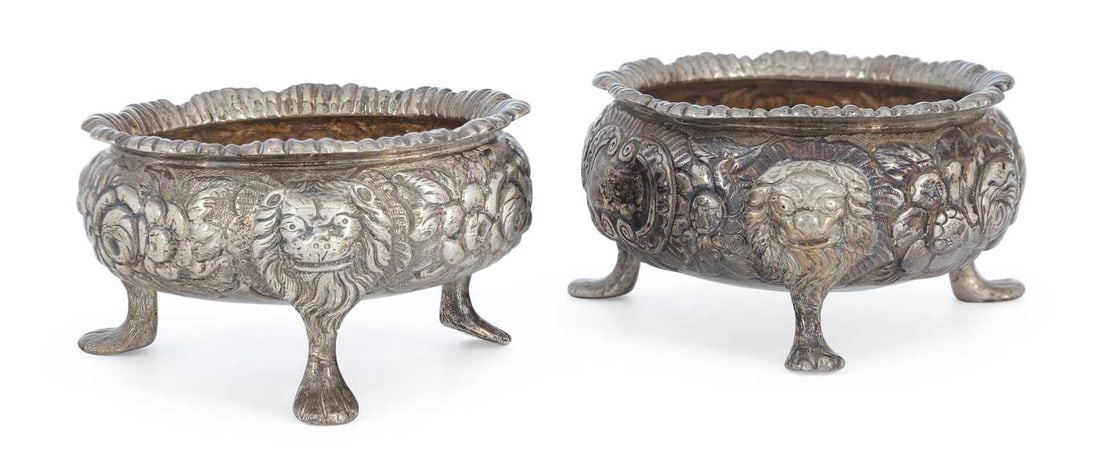 A PAIR OF CONTINENTAL SILVER TABLE SALTS 19TH CENTURY: marks rubbed, of cauldron form with shaped rims, repousse decorated with scrolls and flowerheads, raised on three lion mask and paw feet, with gilded bowls. (2) 7cm diameter, 6 troy ounces gross