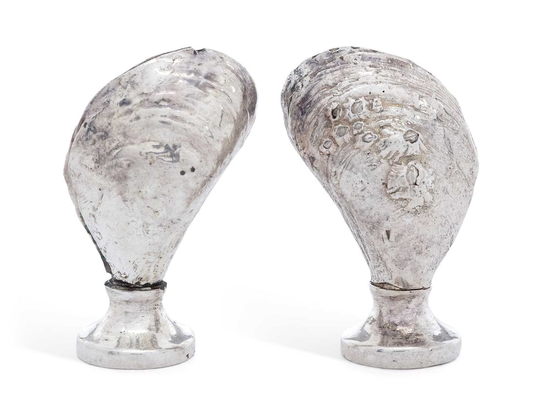 A MATCHED PAIR OF ELIZABETH II NOVELTY SILVER SALT AND PEPPER POTS: by S.M. D. Castings, London 1974 and 1975, realistically modelled in the form of mussel shells with barnacles, circular removable screw off bases. (2) 5.5cm high, 4.2 troy ounces gross