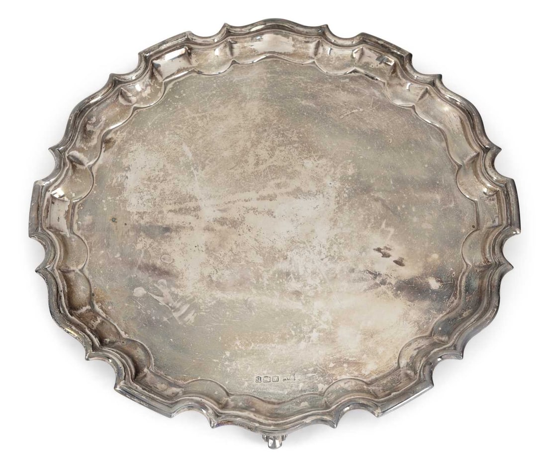 A GEORGE V SILVER SALVER: by Walker & Hall, Sheffield 1919, of shaped circular form with moulded Chippendale border, the centre plain, raised on three feet. 26cm diameter, 15 troy ounces