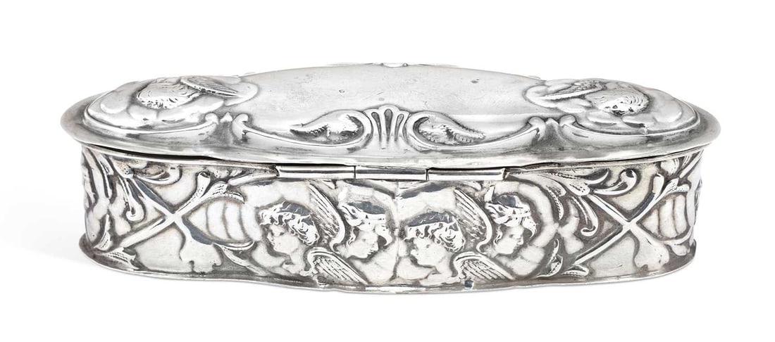 AN EDWARDIAN SILVER TRINKET BOX: maker's mark rubbed, Birmingham 1909, of shaped lozenge form with hinged cover, repousse decorated with winged cherubs within a foliate scroll border. 11cm wide, 1.6 troy ounces Good condition in