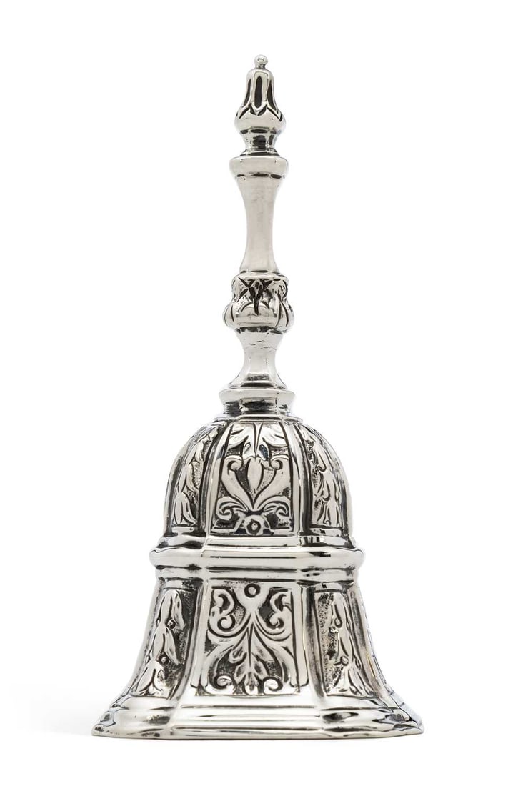AN EDWARDIAN SILVER TABLE BELL: maker's mark unclear, possibly by Goldsmiths & Silversmith Company, London 1904, of shaped octagonal form, with chased foliate decoration, stepped reeded foot and girdle. 10.2cm high, 4.3 troy ounces