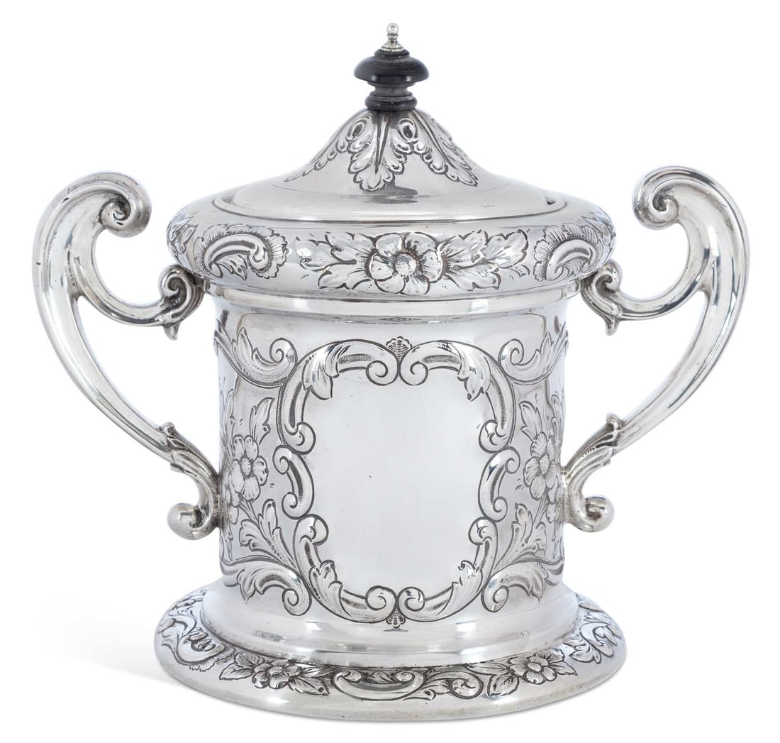 A GEORGE V SILVER TWO-HANDLED BISCUIT BOX: by Charles Weale, Birmingham 1912, of cylindrical form, the partially domed cover chased with acanthus leaves below a turned finial, with two scrolling handles, the body chased with C-scrolls, flowerh
