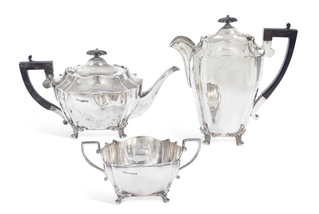 A GEORGE V SILVER PARTIAL TEA AND COFFEE SERVICE: by Needham, Veall & Tyzack Ltd, Sheffield 1910, comprising a coffee pot, teapot and two-handled sugar bowl, each of fluted shape with shaped rims, foliate-capped feet and angular handles. (3) Coffee