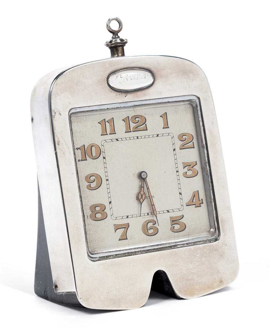 AUTOMOBILIA INTEREST: A RARE GEORGE V SILVER MOTORING THEMED DESK CLOCK: by Joshua Williams & Co. (David Fullerton), London 1929, the clock case modelled as a radiator grille, the square silvered dial with Arabic numerals, Swiss made, on ebonised frame. 13cm high