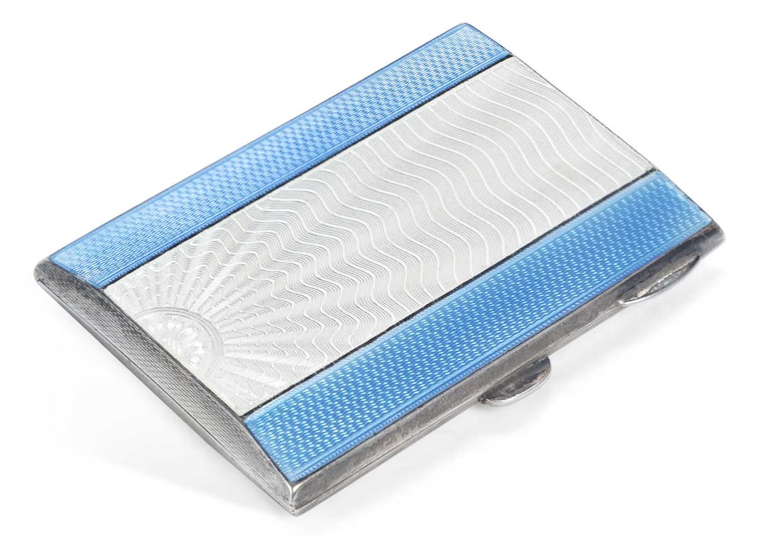 A GEORGE V SILVER AND ENAMEL CIGARETTE CASE: by Turner & Simpson Ltd., Birmingham 1935 (Jubilee hallmark), of rectangular form, with a hinged cover decorated with panels of blue and white enamel with radiating and geometric pattern. 8cm wide,