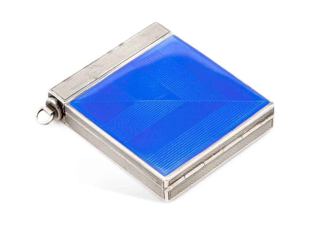 A CONTINENTAL SILVER AND ENAMEL COMPACT: import marked, of square form, with blue enamel and engine-turned decoration, the interior gilded opening to a mirror and powder puff. 5.5cm by 5cm by 1cm, 3.1 troy ounces gross