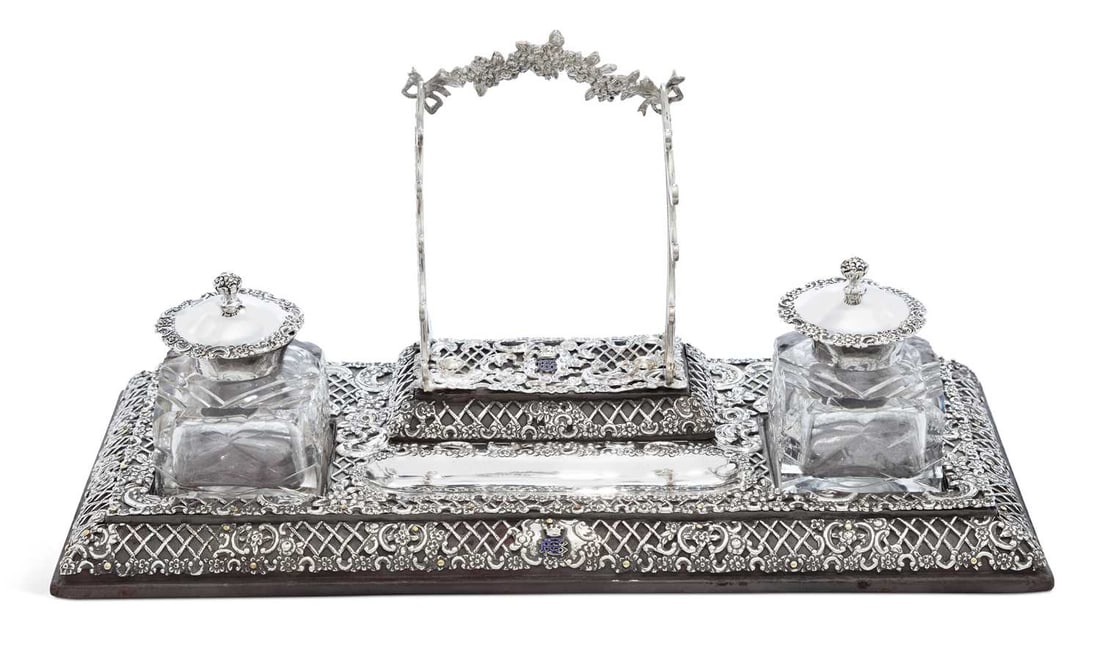A LATE VICTORIAN SILVER DESK STAND: by William Comyns & Sons, London 1893, of pierced rectangular form with repeating lattice motif decoration inset with scrolls and flowerheads, bearing enamelled monogram surmounted by a coronet, with 