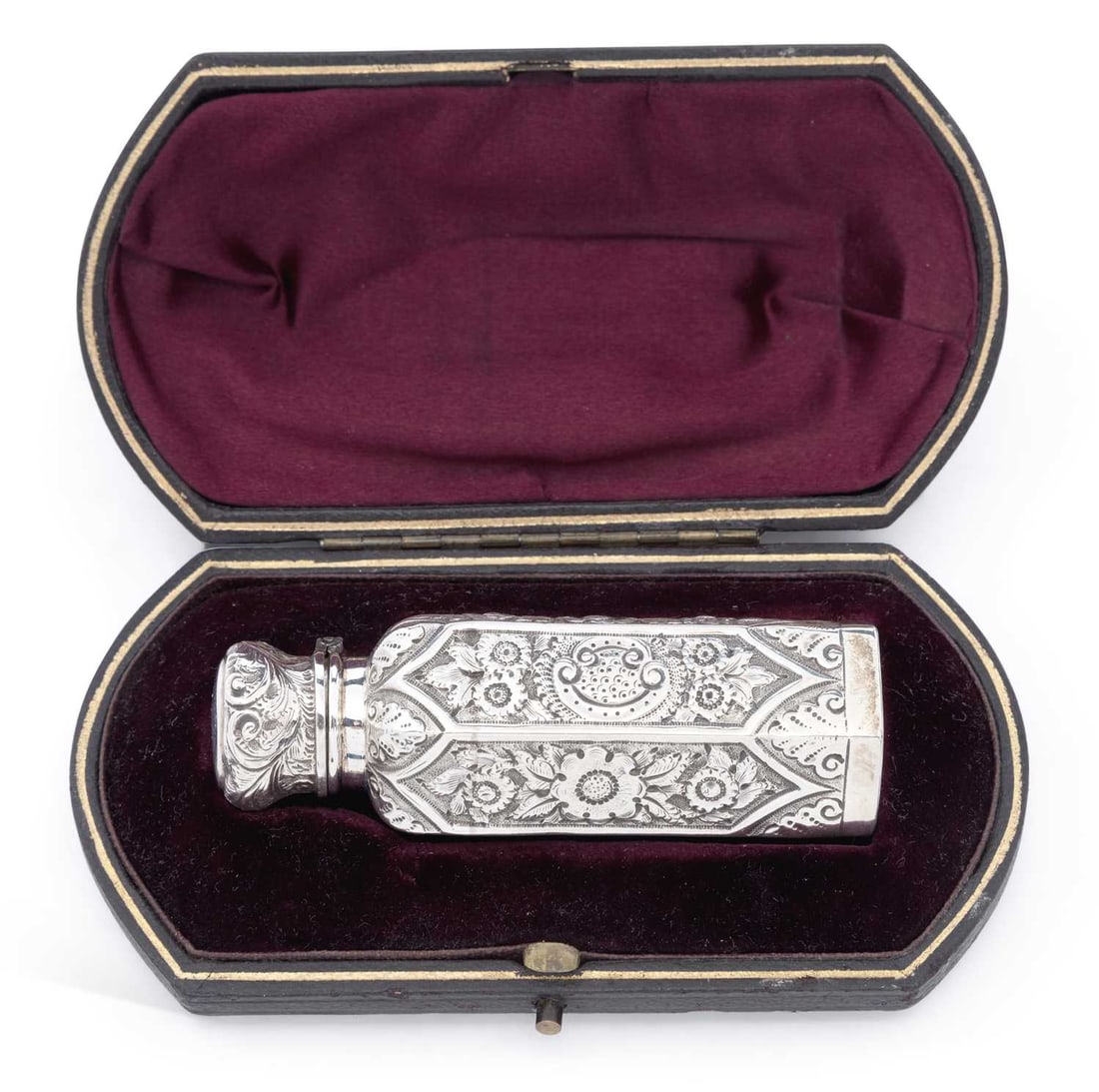 A LATE VICTORIAN SILVER-CASED SCENT BOTTLE: by Hilliard & Thomason, Birmingham 1896, of hexagonal form with hinged cover, the glass bottle overlaid with repousse scrolling foliate decoration, to a fitted velvet and silk-lined leather case.