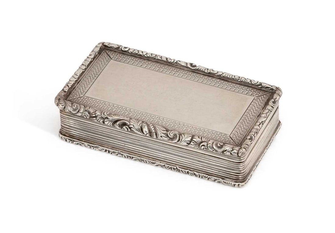 A WILLIAM IV SILVER SNUFF BOX: by Francis Clark, Birmingham 1836, rectangular, with hinged cover, cast foliate and scroll rim, with engine-turned decoration, reeded sides and gilt wash interior. 7.6cm by 4.2cm by 1.7cm, 2.7 troy ou