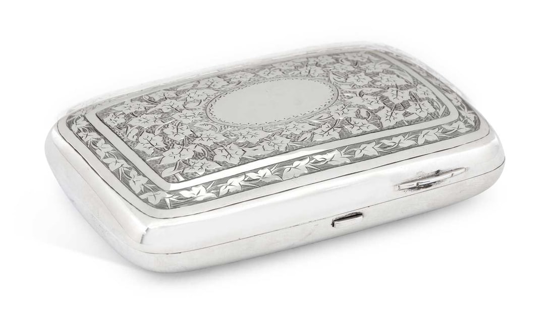 A VICTORIAN SILVER CIGARETTE CASE: by Hilliard & Thomason, Birmingham 1881, of rectangular form with rounded sides, the hinged cover and base profusely engraved with foliate pattern, vacant cartouche, with silver gilt interior. 11cm