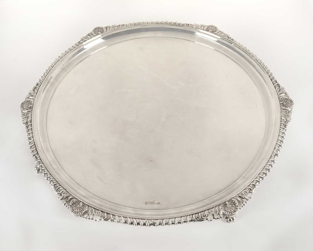 A VICTORIAN SILVER SALVER: by Atkin Brothers, Sheffield 1895, of shaped circular form, the border cast with shells and foliate scrolls above a gadrooned edge, the centre plain, raised on four scroll feet. 50cm diameter, 83.8