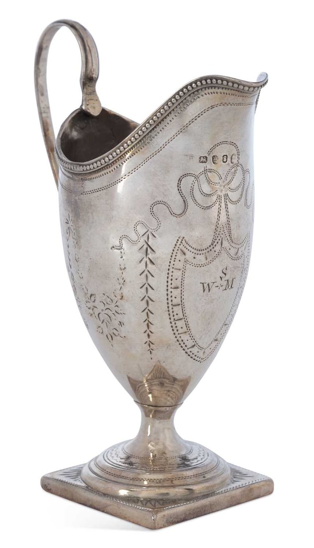 A GEORGE III SILVER CREAM JUG: maker's mark worn, London 1793, ovoid form with a high looped handle and square pedestal foot, the shaped rim decorated with a beaded border, engraved with chevron patterns flanked by foliate motifs, 