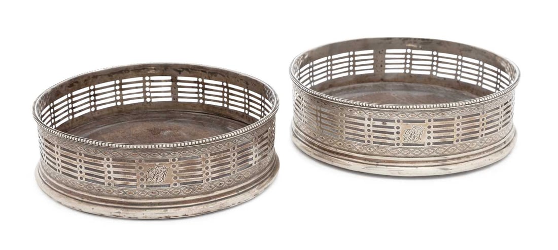 A PAIR OF GEORGE III SILVER WINE BOTTLE COASTERS: by Thomas Daniell, London 1777, of circular form, the pierced gallery with bright cut engraving and beaded borders, monogram engraved. (2) 12cm diameter Gallery condition good overall commensurate wit