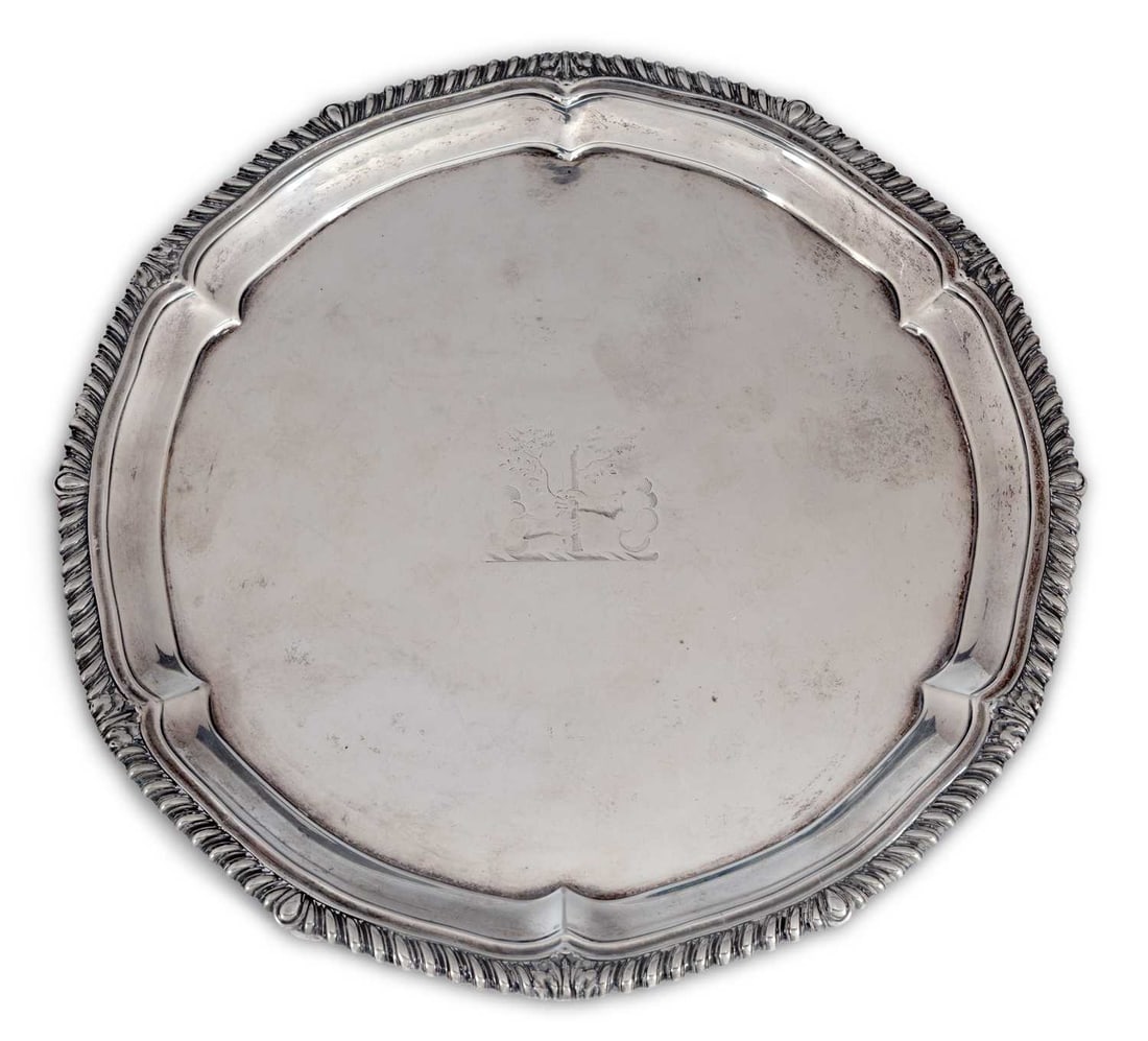 A GEORGE III SILVER SALVER: by Paul Storr, London 1814, of shaped circular form with a gadrooned border, the centre engraved with a crest, raised on four feet. 30.5cm diameter, 26.5 troy ounces