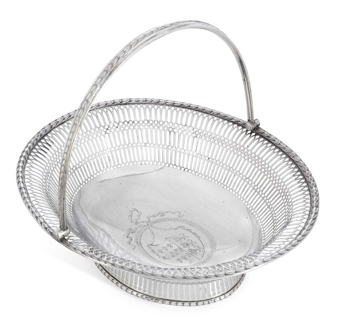 A GEORGE III SILVER PIERCED BASKET: by Charles Aldridge & Henry Green, London 1775, of oval form with swing handle, pierced with geometric pattern, borders with repeating leaf pattern, on pierced foot, engraved to centre with an