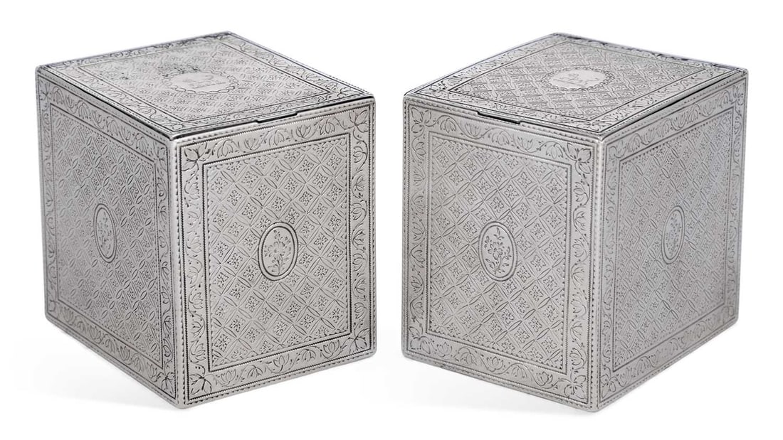 A PAIR OF GEORGE III SILVER TEA CADDIES: maker ED, London 1774, of rectangular form with a hinged cover, engraved with a repeating flowerhead pattern within a boarder of foliate scrolls, engraved with a crest. 9cm high, 7cm wide, 8.3 troy ou
