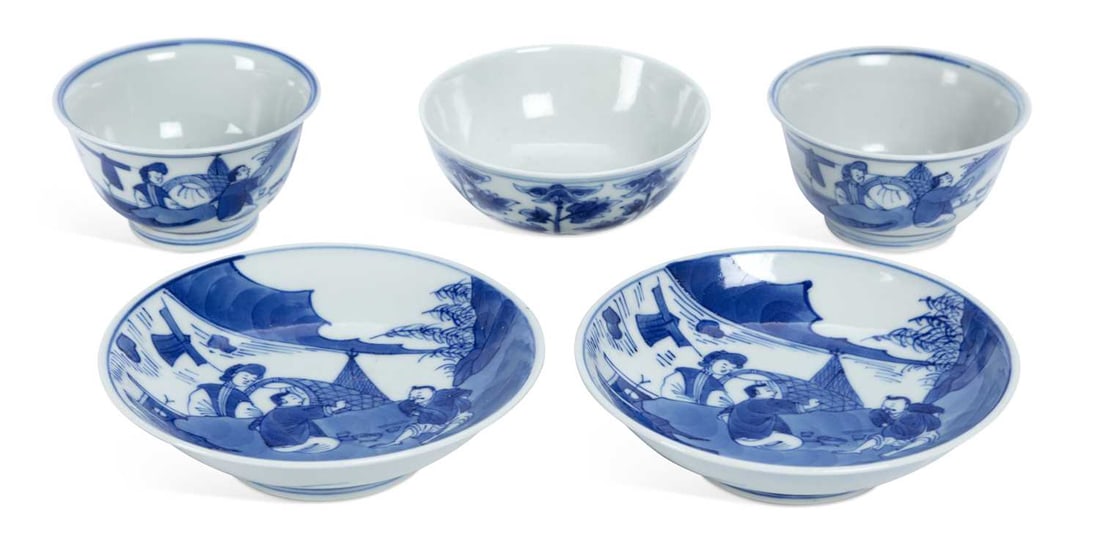 A PAIR OF CHINESE BLUE AND WHITE TEABOWLS AND SAUCERS: painted in underglaze blue, with figures eating beside a boat on a river, and a tea bowl painted with flowering plants. (5) Saucers 11.5cm diameter