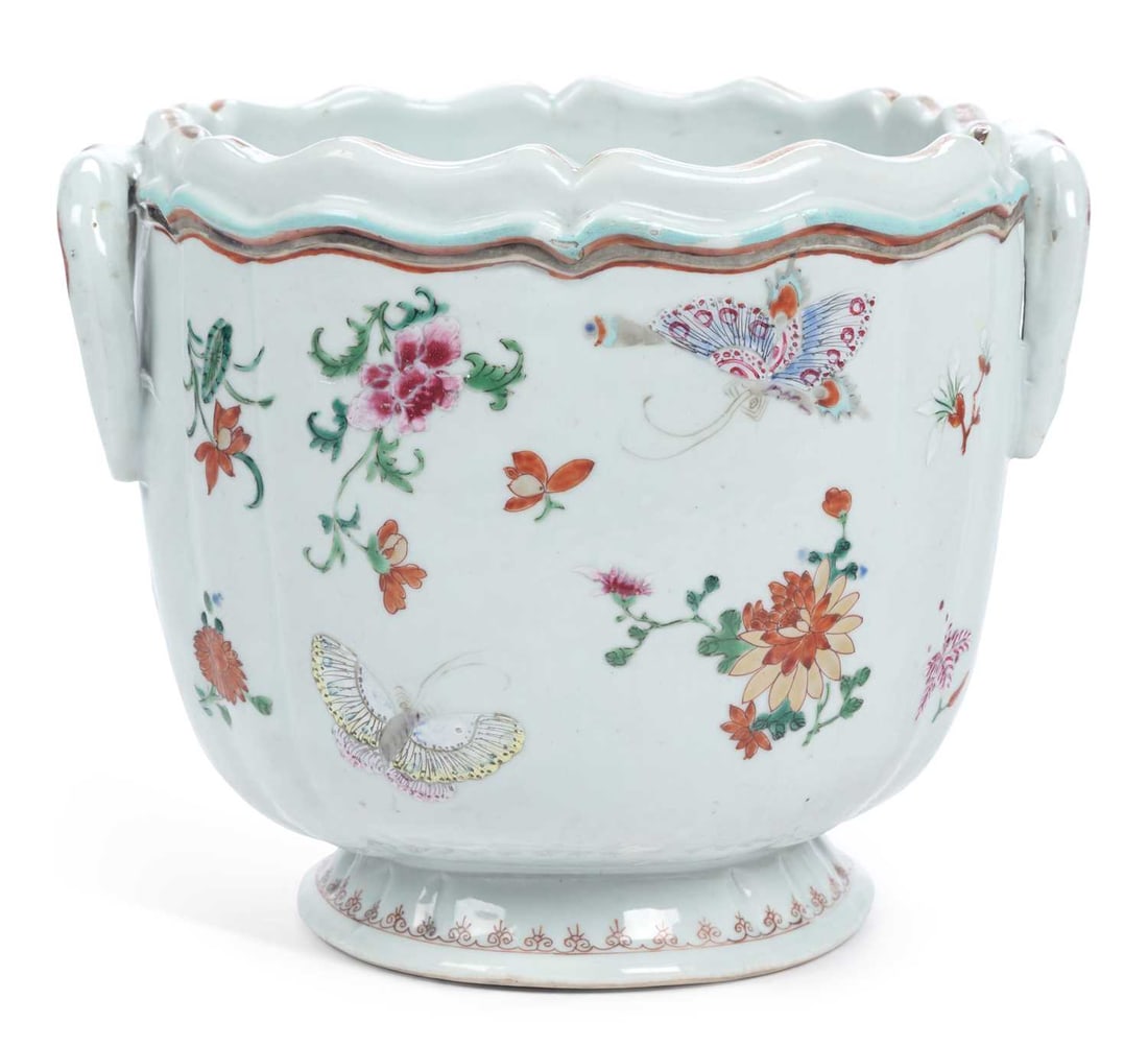 A CHINESE EXPORT FAMILLE ROSE WINE COOLER: Qianlong period, of fluted form with a shaped and lobed rim and twin loop handles with iron-red scroll terminals, painted in famille rose enamels with butterflies among scattered flower sprays, the ri