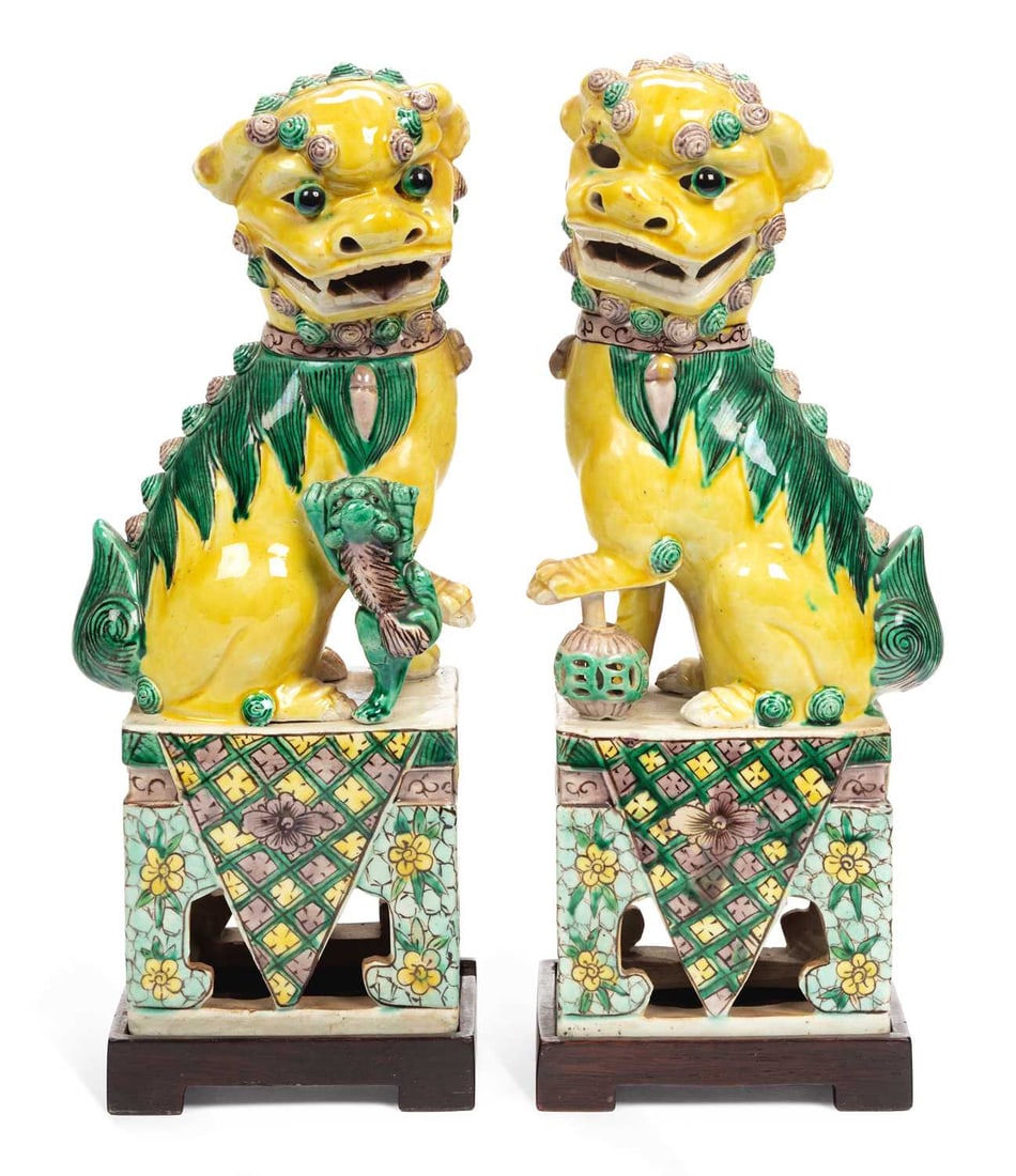 A PAIR OF CHINESE LION DOGS CIRCA 1900: the seated lion dogs, decorated in famille verte enamels, and set upon pierced rectangular cabriole style bases, on wooden stands. (2) 26cm high