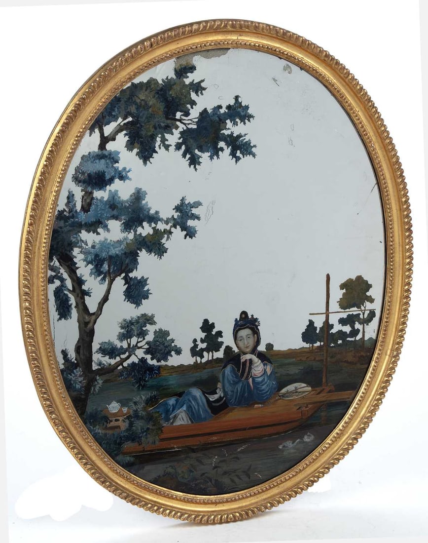 A CHINESE EXPORT REVERSE PAINTING ON MIRROR 18TH CENTURY: of oval form, depicting a courtesan reclining in a sampan with a teapot and cup beside her, before a river landscape with willow and pine, the silvering reserved to the sky and water, within a carved 