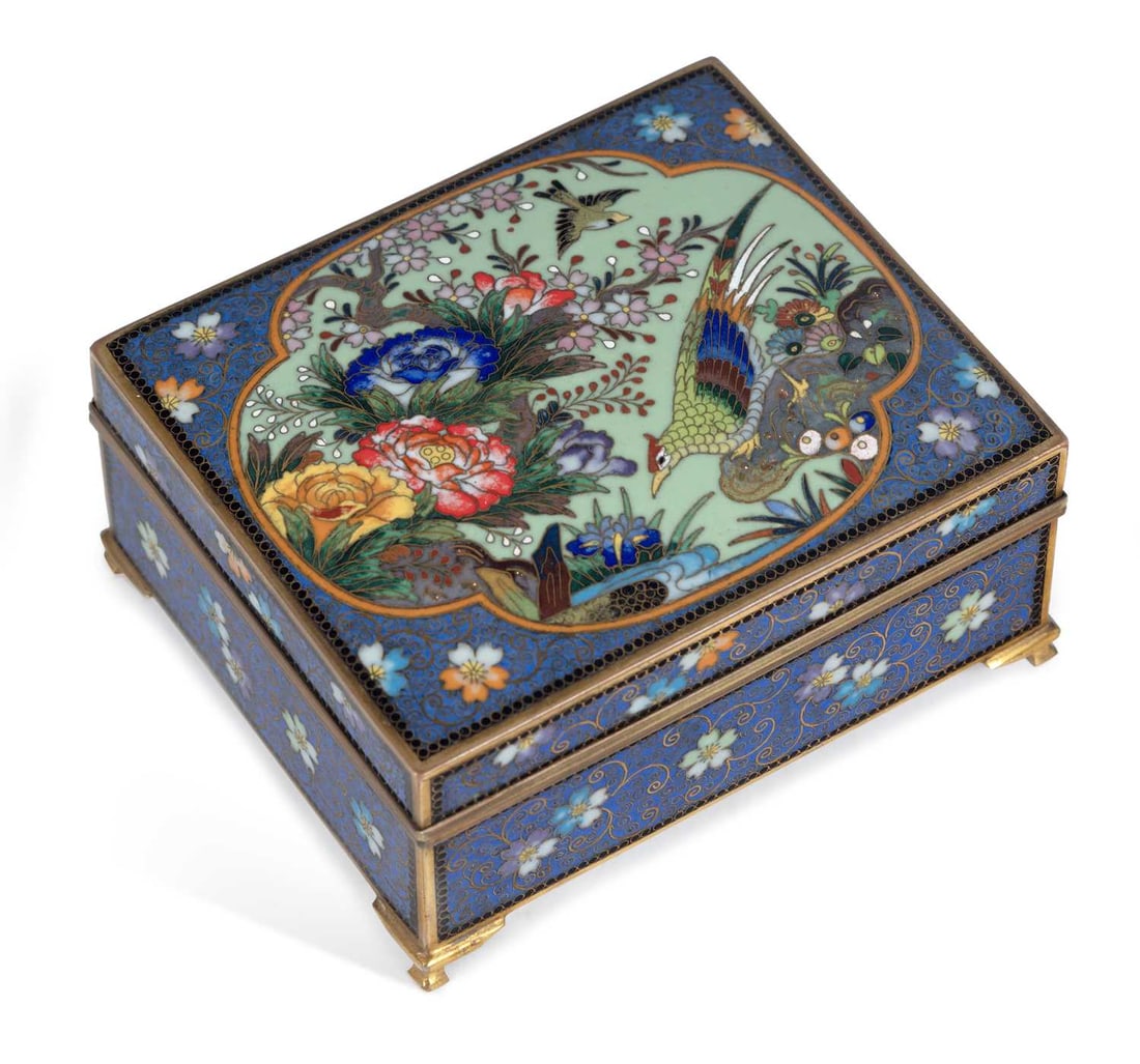 A JAPANESE CLOISONNE BOX MEIJI PERIOD: the box set upon four cabriole feet and decorated in enamel with a panel of a pheasant perched on a rock, above a river, the sides with continuous floral scroll. 10.8cm long, 5cm high