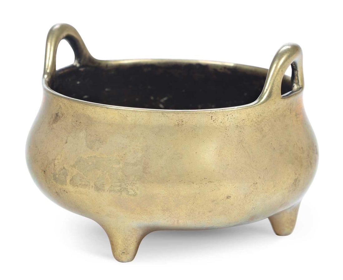 A CHINESE BRONZE CENSER QING DYNASTY: the twin handled censer set upon three stub feet, apocryphal Xuande six character seal mark to the base. 10.4cm diameter